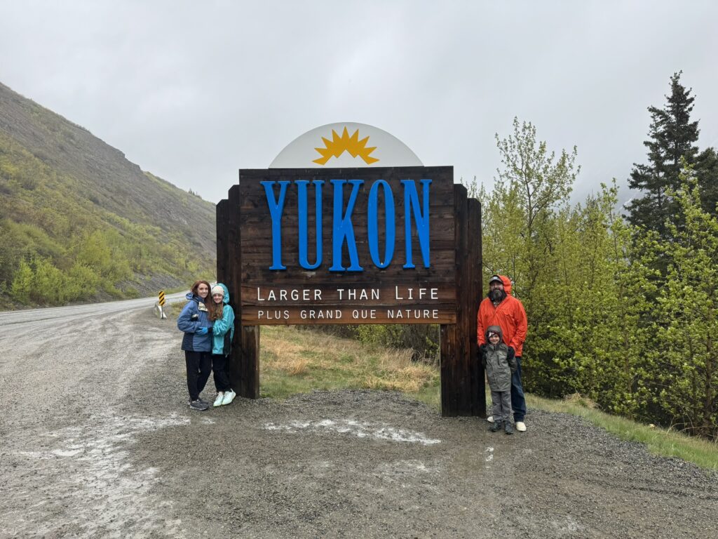 family posing next to welcome to the Yukon sign.