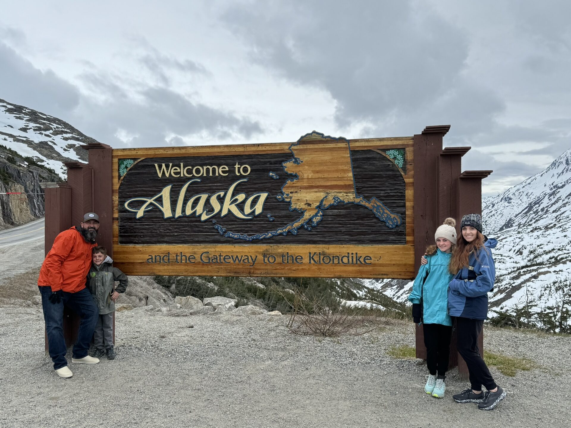 family at Welcome to Alaska sign